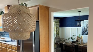 Een moderne keuken met houten kastjes, een roestvrijstalen koelkast en een hanglamp.