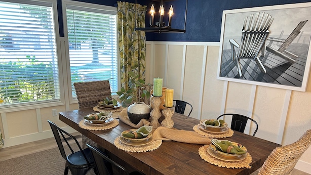 Een eetgedeelte met een houten tafel, gedekt voor vier personen, omringd door rieten stoelen.
