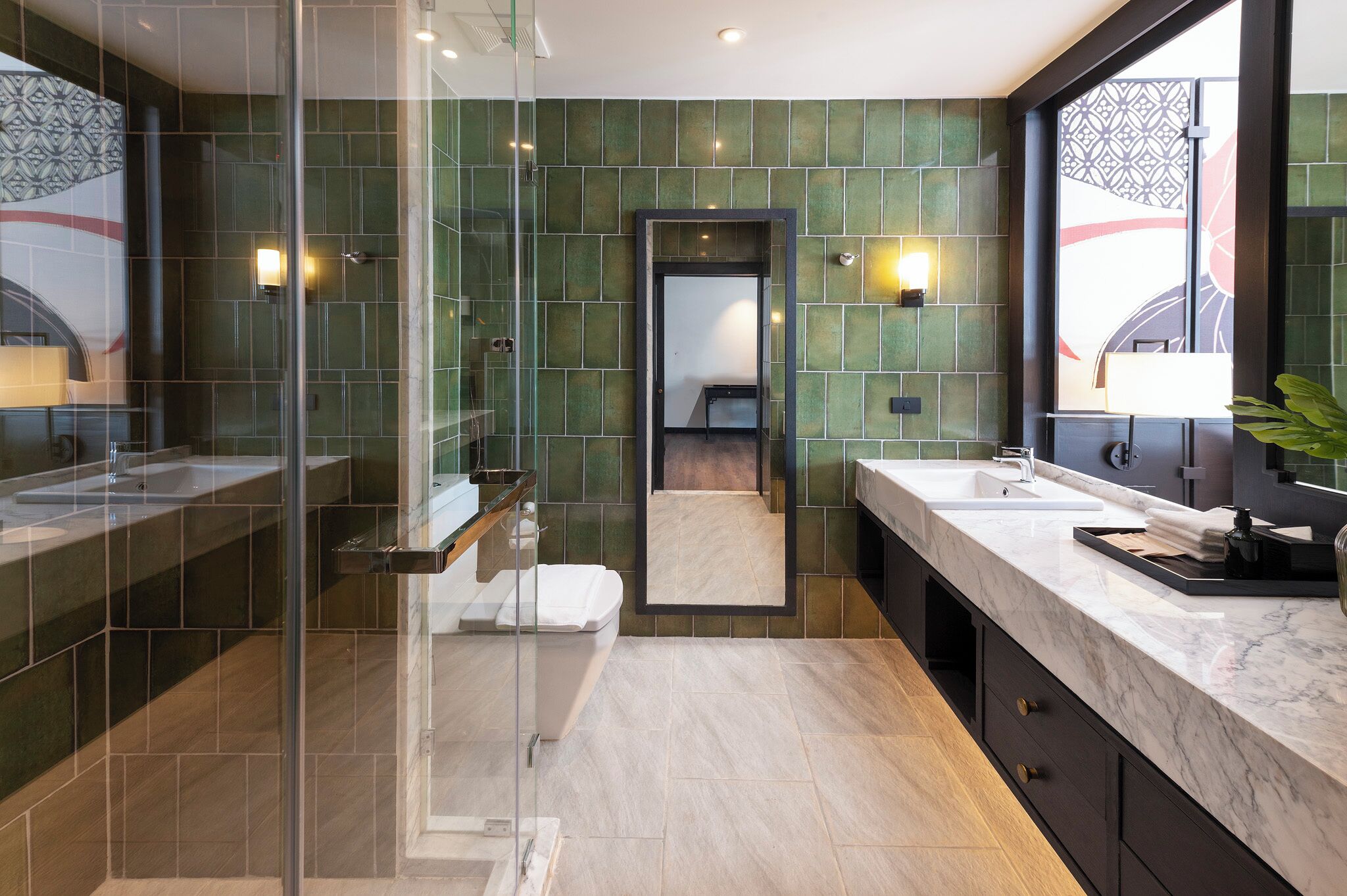 A modern bathroom with a glass shower enclosure, a large mirror, and a vanity with a marble countertop.
