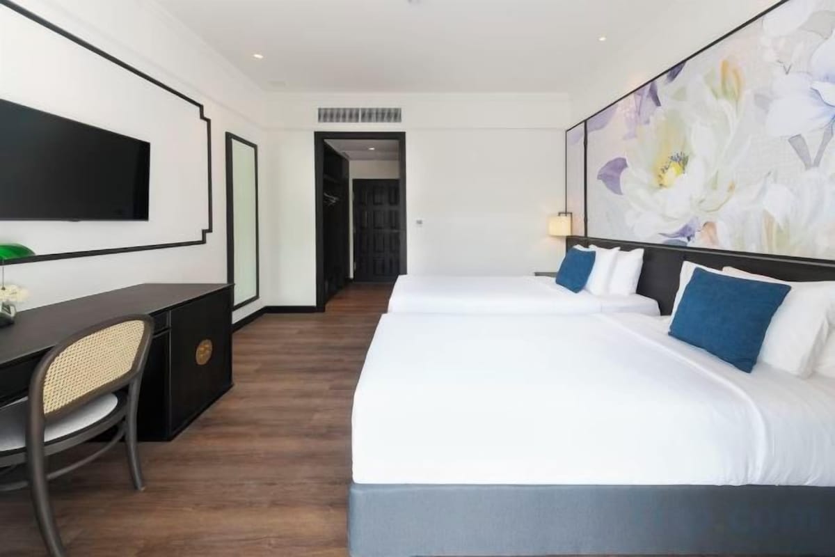 A hotel room with a large bed, a desk, and a television.