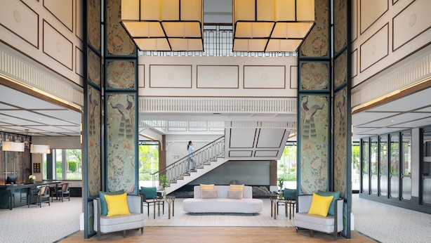 A spacious lobby with a central seating area, a staircase, and a reception desk.