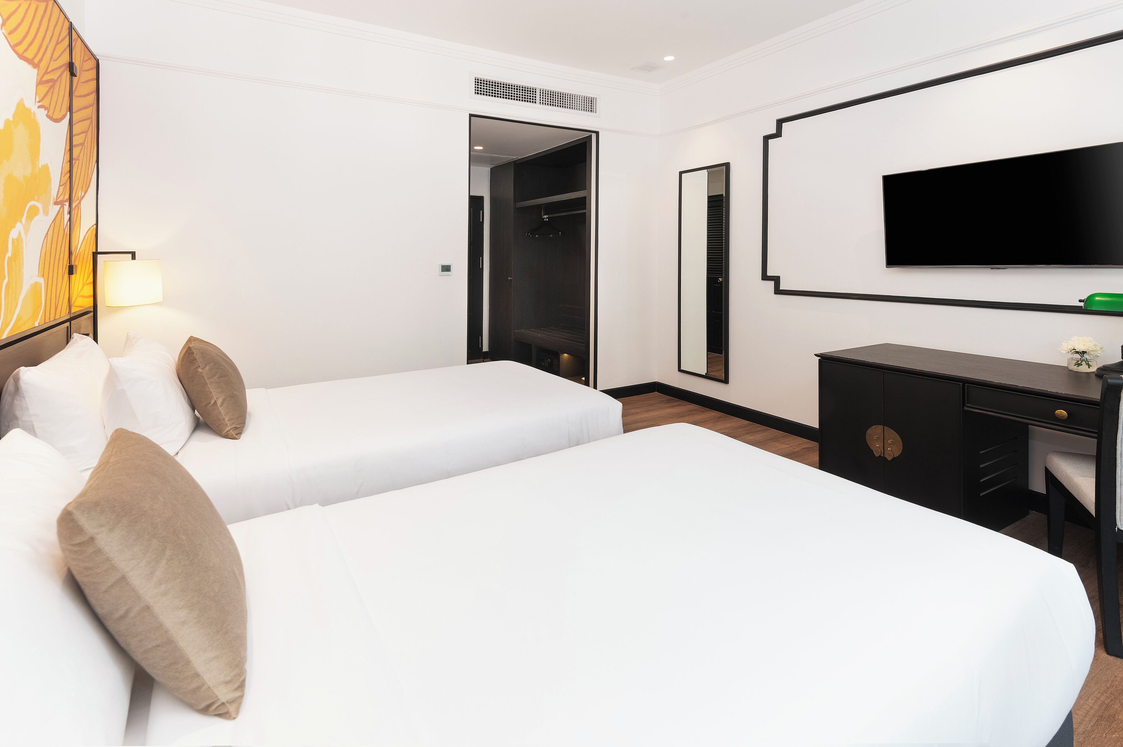 A hotel room with two beds, a TV, a wardrobe, and a desk.