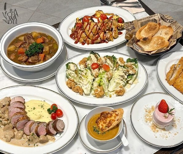 Una variedad de platos sobre una mesa, como sopa, ensalada y guisos de carne.