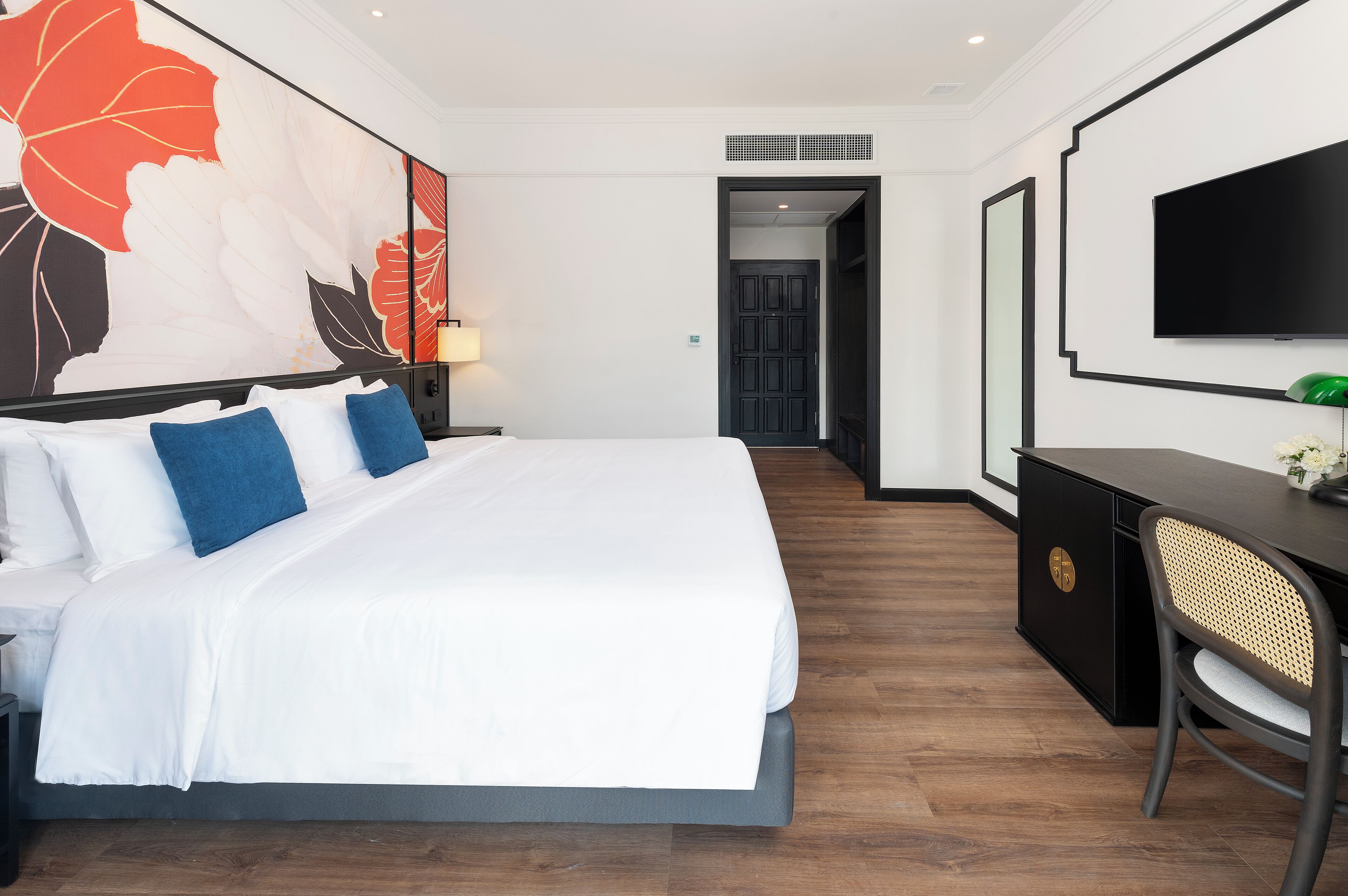 Una habitación de hotel moderna con una cama grande, un escritorio y un televisor.