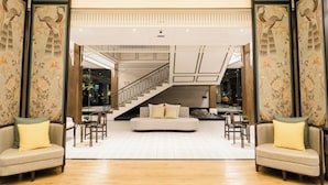 A spacious lobby with a central seating area, a staircase, and decorative panels.