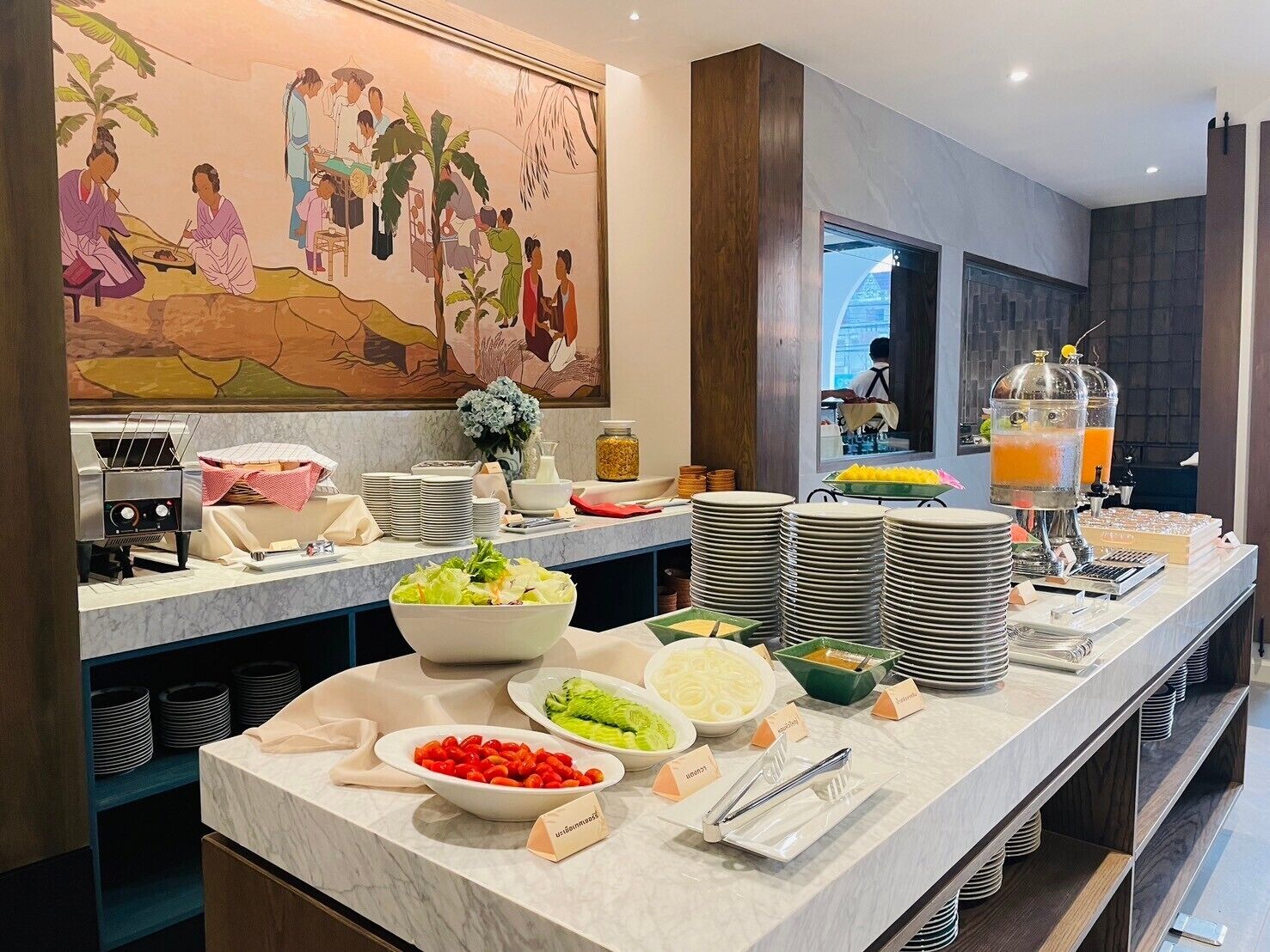 A buffet setup with various food items and a juice dispenser.