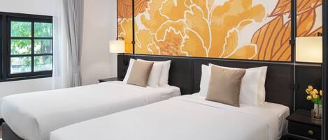 Habitación de hotel con dos camas, un ventanal con cortinas y un mural en la pared.