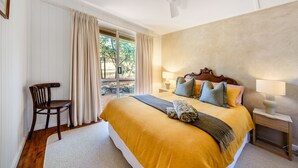 Un dormitorio con una cama grande, una silla, una mesita de noche y una ventana con cortinas.