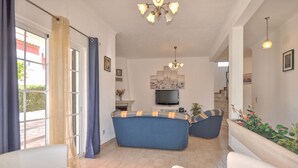 Un salon avec un canapé, un téléviseur et un escalier menant à un autre niveau.
