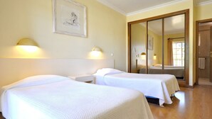 Quarto de hotel com duas camas, um espelho grande e luminárias fixadas na parede.