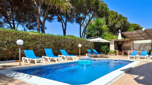 A swimming pool with blue lounge chairs and a small building in the background. - Relax in a 5-bedroom villa with a private pool in Vilamoura. (Vilamoura)