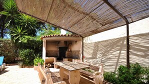An outdoor patio area with a wooden table and benches, a grill, and a pergola providing shade. - Relax in a 5-bedroom villa with a private pool in Vilamoura. (Vilamoura)