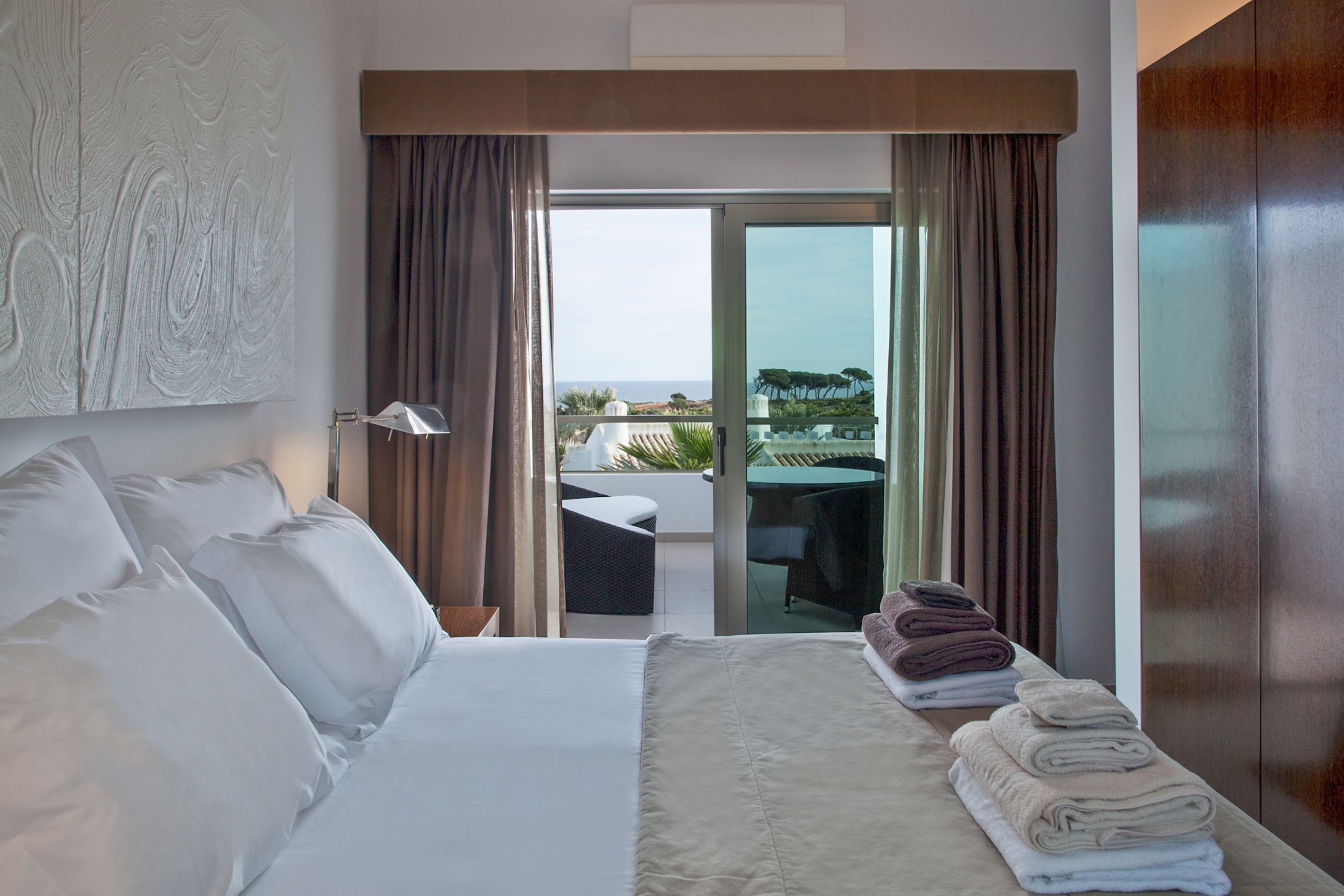 Una habitación de hotel con cama, una mesa con sillas y vista al océano.