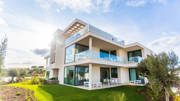 Una casa moderna de dos pisos con amplios ventanales, un balcón y un jardín cuidado.