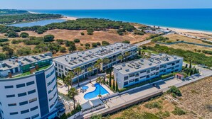 Ein modernes Hotel mit Dachpool, umgeben von Grün und Blick auf das Meer.