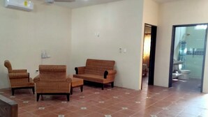 A living room with a sofa, two armchairs, and a ceiling fan. There is a tiled floor and a door leading to a bathroom. - Casa La Paz  (Merida)