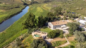 Una casa con piscina, rodeada de vegetación y un río.