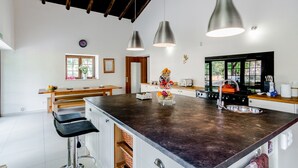 Una cocina moderna con una isla grande, luces colgantes y vistas al exterior.