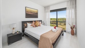 Un dormitorio moderno con una cama grande, una mesita de noche, una ventana con vistas y un cuadro en la pared.