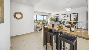 Una cocina moderna con una isla central, taburetes de bar y un rincón comedor con sofá.