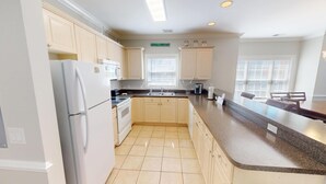 A modern kitchen with light wood cabinets, a granite countertop, and a built-in oven.