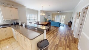 A modern kitchen with a central island, wooden flooring, and light-colored cabinetry.