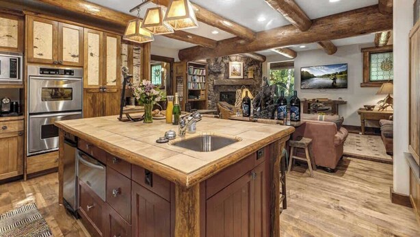 A kitchen with wooden cabinets, a large island, and a stone fireplace.