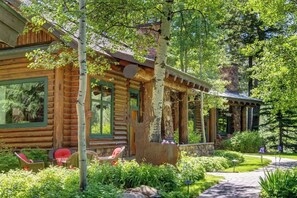 Une cabane en rondins avec un porche, un espace salon extérieur et un jardin.