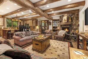 Ein gemütliches Wohnzimmer mit Kamin, Holzbalken, einer Steinwand und einem Bücherregal.