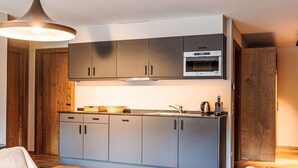 Une cuisine moderne avec des meubles gris, un four à micro-ondes encastré et une table à manger en bois.