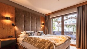 Une chambre moderne avec un grand lit, une tête de lit en bois et une vue sur une montagne.