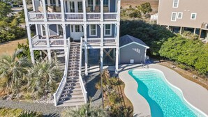 Una casa de varios pisos con porche cubierto, piscina y garaje.