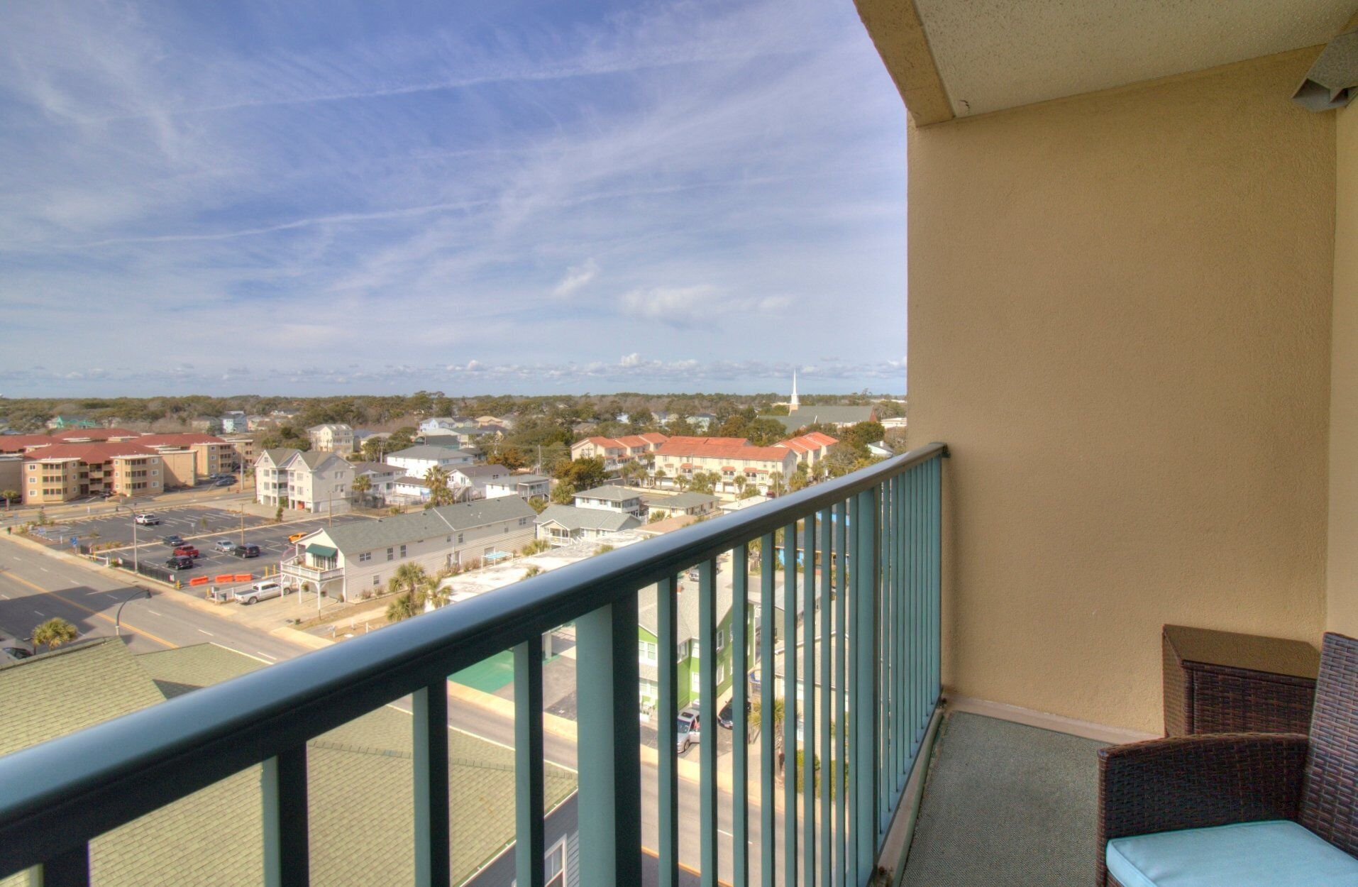 Un balcone con vista su una zona residenziale, tra case e il campanile di una chiesa.