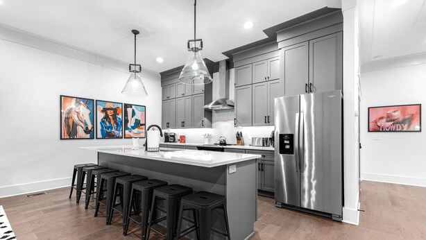 A modern kitchen with grey cabinets, stainless steel appliances, and a central island with bar stools. - NEW! Nash Honky-Tonk w/Game Room, Arcade's, and Pool Table  (Nashville)