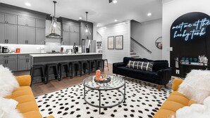 A modern kitchen with grey cabinets, a central island, and black bar stools. - NEW! Nash Honky-Tonk w/Game Room, Arcade's, and Pool Table  (Nashville)