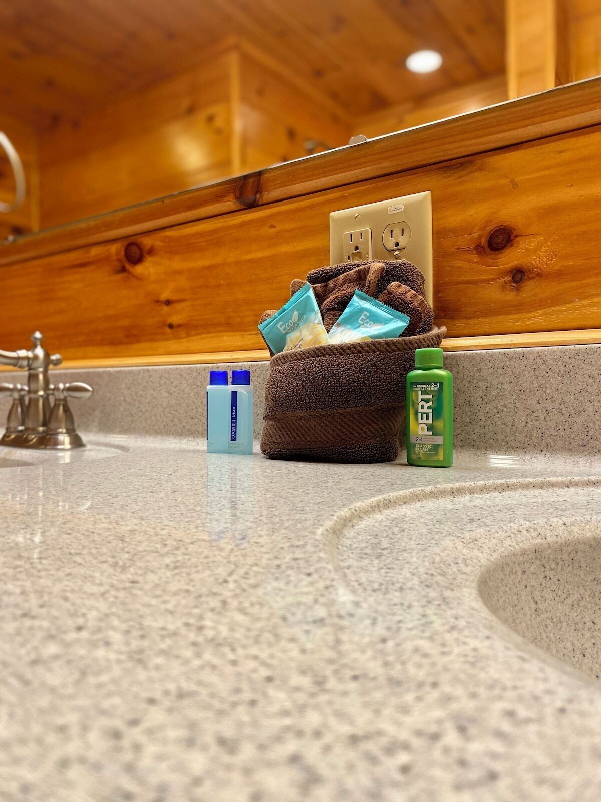 Un lavabo in bagno con articoli da toilette, un asciugamano e una bottiglia verde.