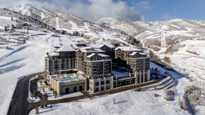 Ein mehrstöckiges Hotel mit einer Skipiste im Hintergrund.