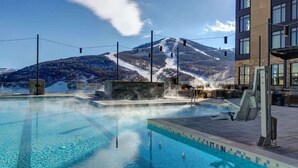 Ein Pool mit Blick auf die Berge, eine Sauna und ein Gebäude mit großen Fenstern.
