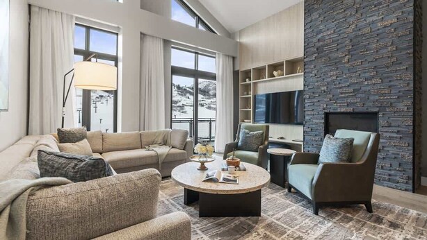 Ein modernes Wohnzimmer mit einer Couch, Sesseln, einem Couchtisch und einem Kamin.