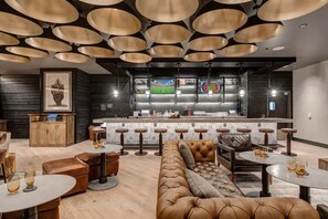A modern bar area with a counter, stools, and a seating area with a sofa and tables. - Abode at Deer Valley East, hot tub, pool, resort access, Deer Valley (Park City)