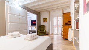 Une chambre d’hôtel avec un lit, un fauteuil vert, une armoire en bois et une bibliothèque.