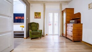 Une pièce avec un fauteuil vert, une commode en bois et une porte donnant sur un balcon.