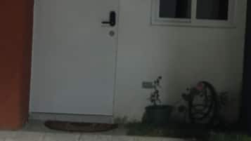 Een witte deur met het nummer 12, een klein raam en een bloempot ernaast.