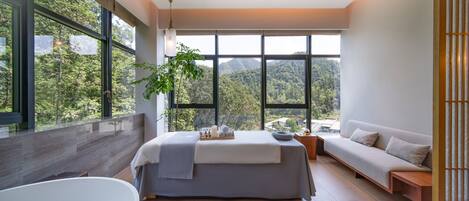 A modern bedroom with a large bed, a bathtub, and a sofa.
