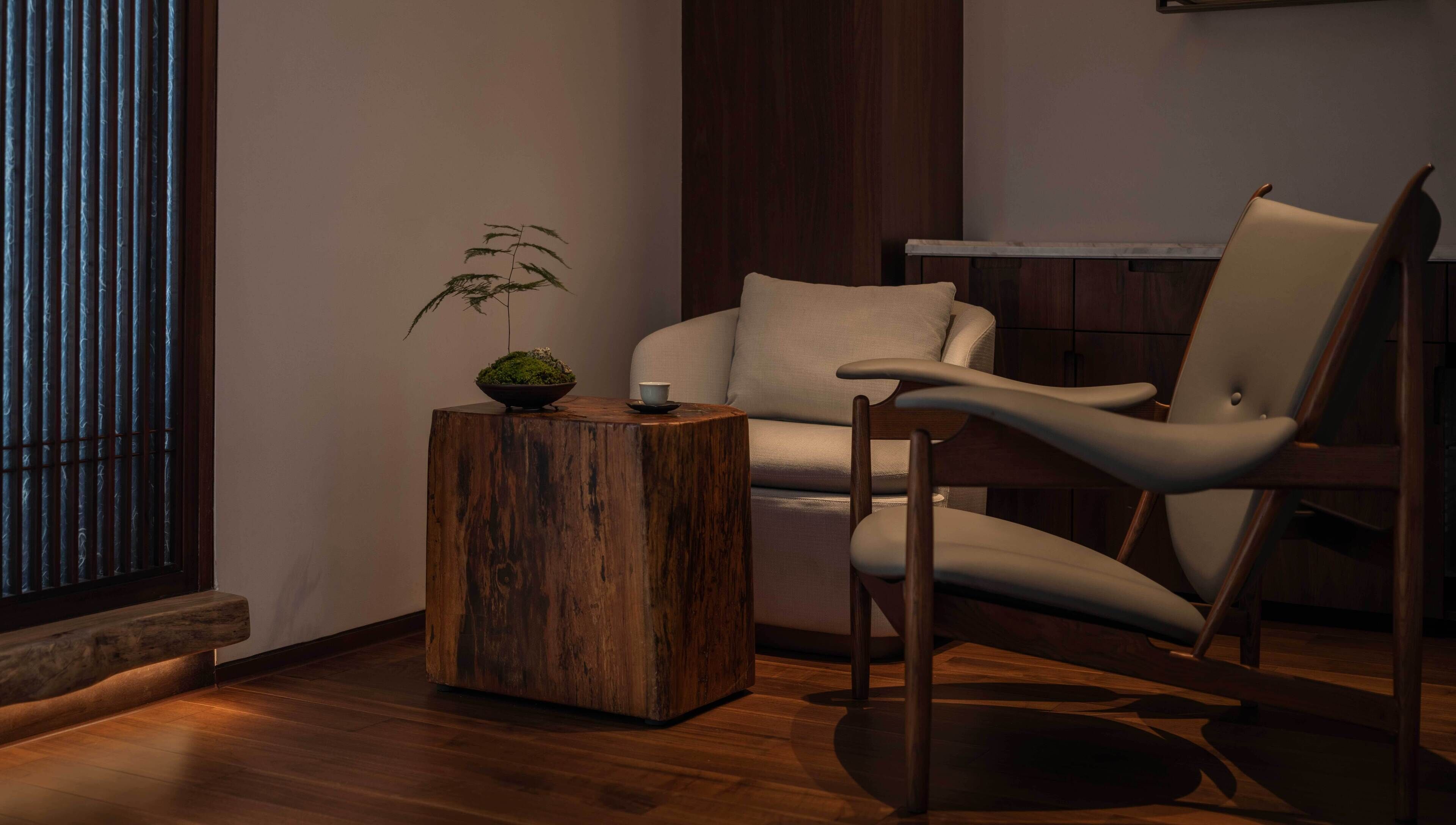 A modern living room with a wooden coffee table, a chair, and a potted plant.