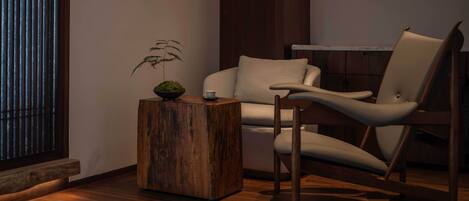 A modern living room with a wooden coffee table, a chair, and a potted plant.