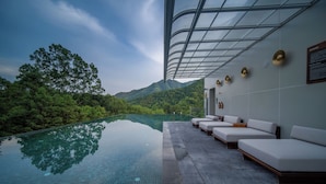 Ein moderner Infinity-Pool mit freiem Blick auf üppiges Grün und Berge im Hintergrund.