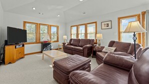 A spacious living room with leather sofas, a television, and a fireplace. - 1750 - Cool Winds, Corolla Beach House: Private Pool & Hot Tub (Corolla)