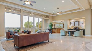 A spacious living area with a leather sofa, a dining table, and a kitchen area with a bar.