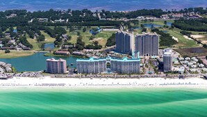 Un resort costero con varios edificios altos, una playa y vegetación circundante.